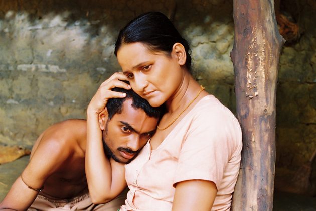Two figures resting against a mud wall.